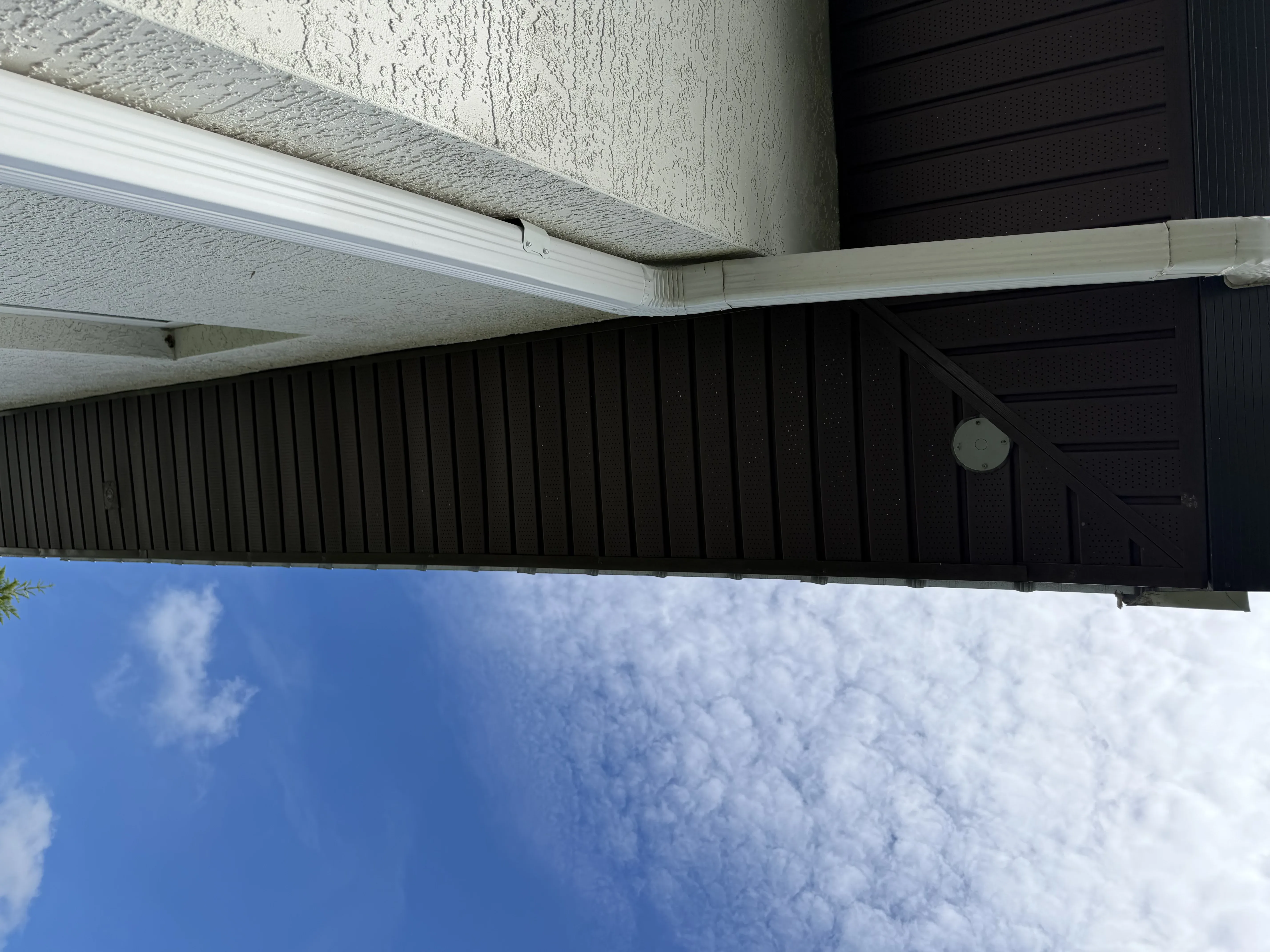 Metal roof with white seamless gutter and soffit installation on residential property