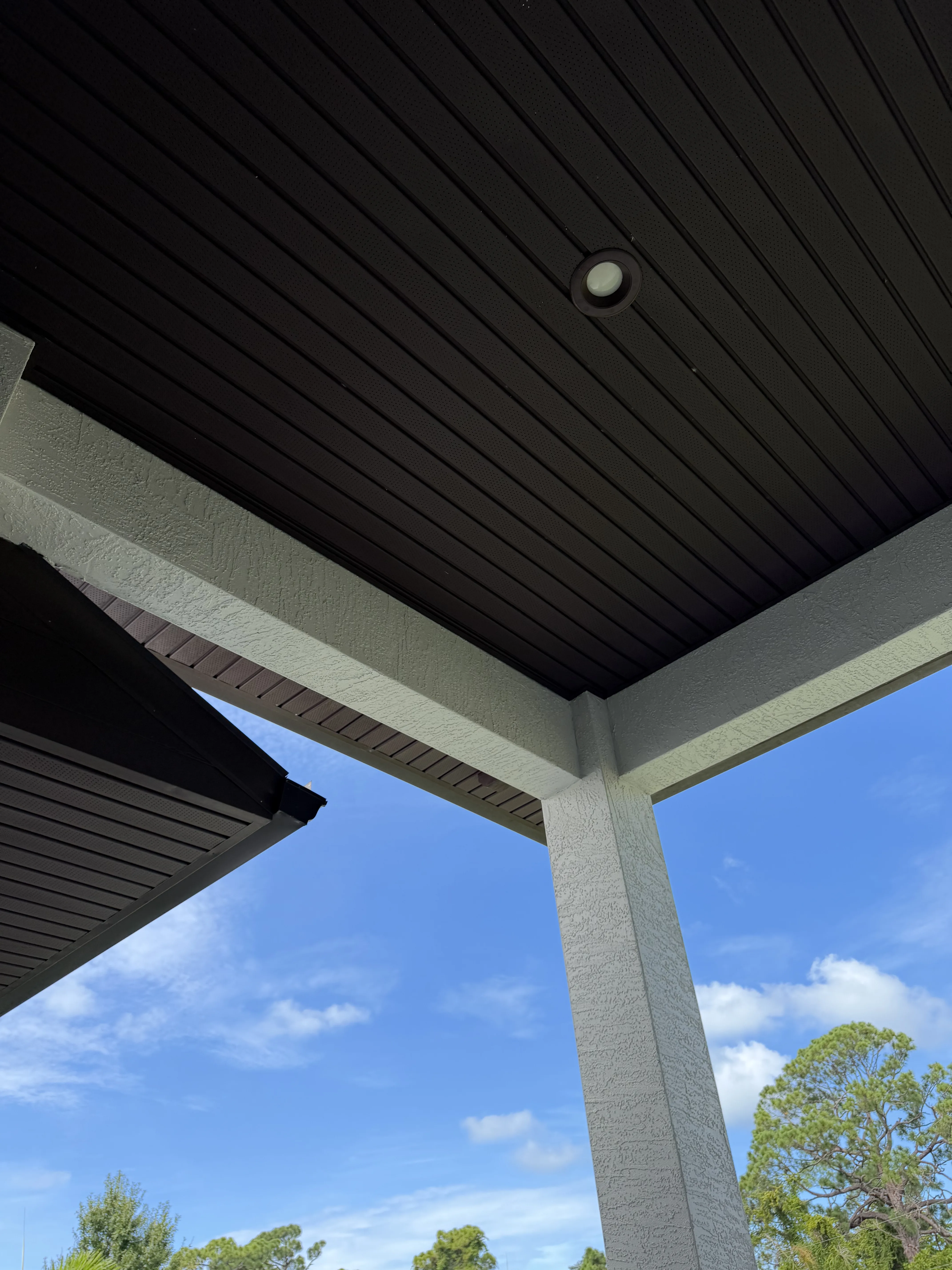 Black standing seam metal roof with white soffit and fascia trim installed under residential eave
