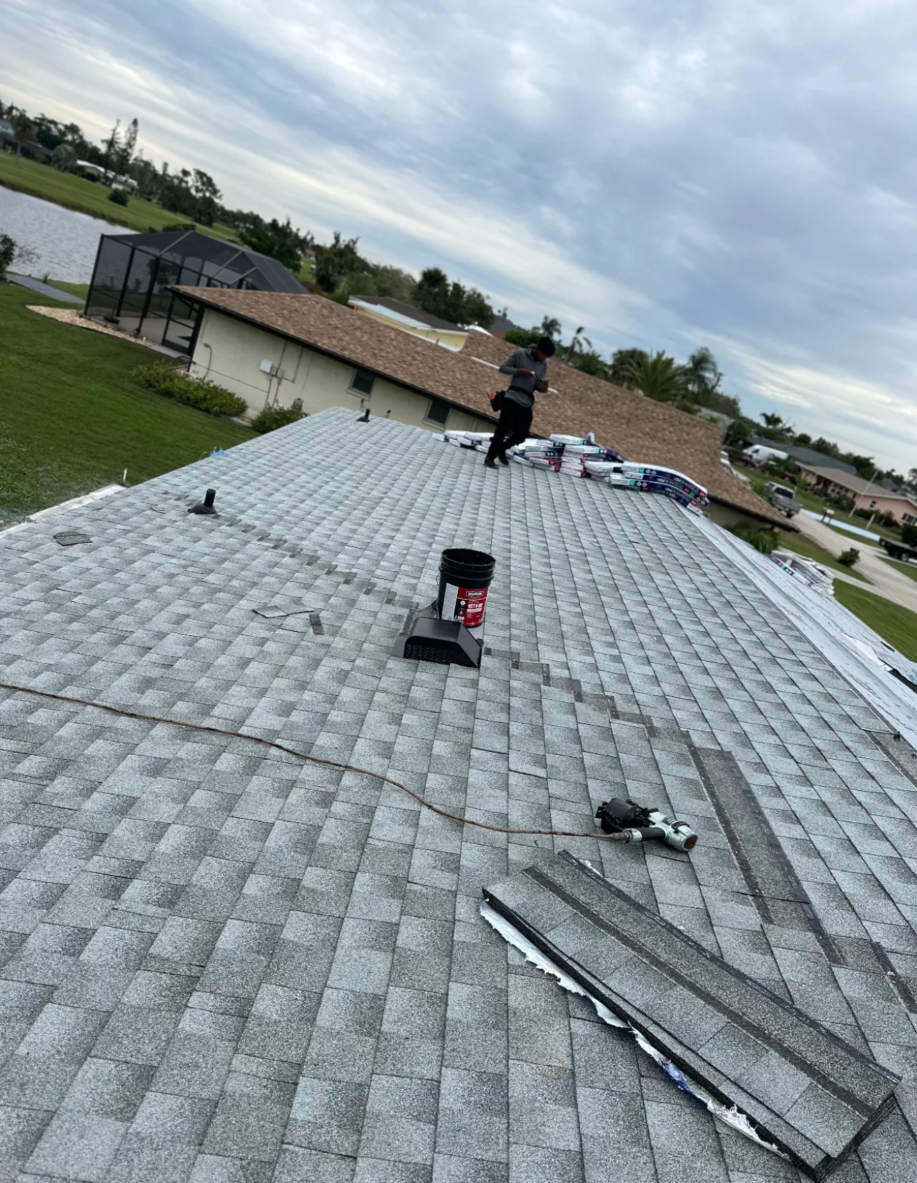 Professional installing gray asphalt shingles on residential roof during shingle roof replacement