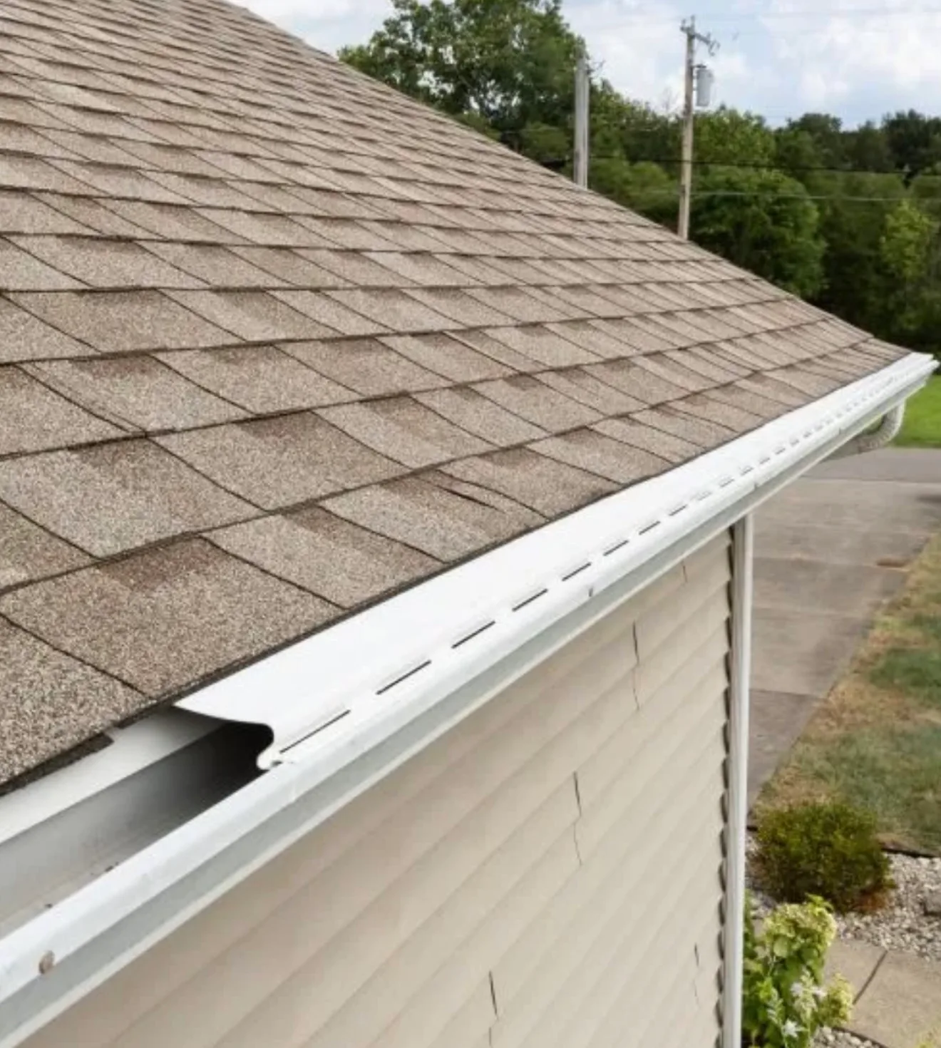Residential asphalt shingle roof with white seamless gutter installation along the roofline