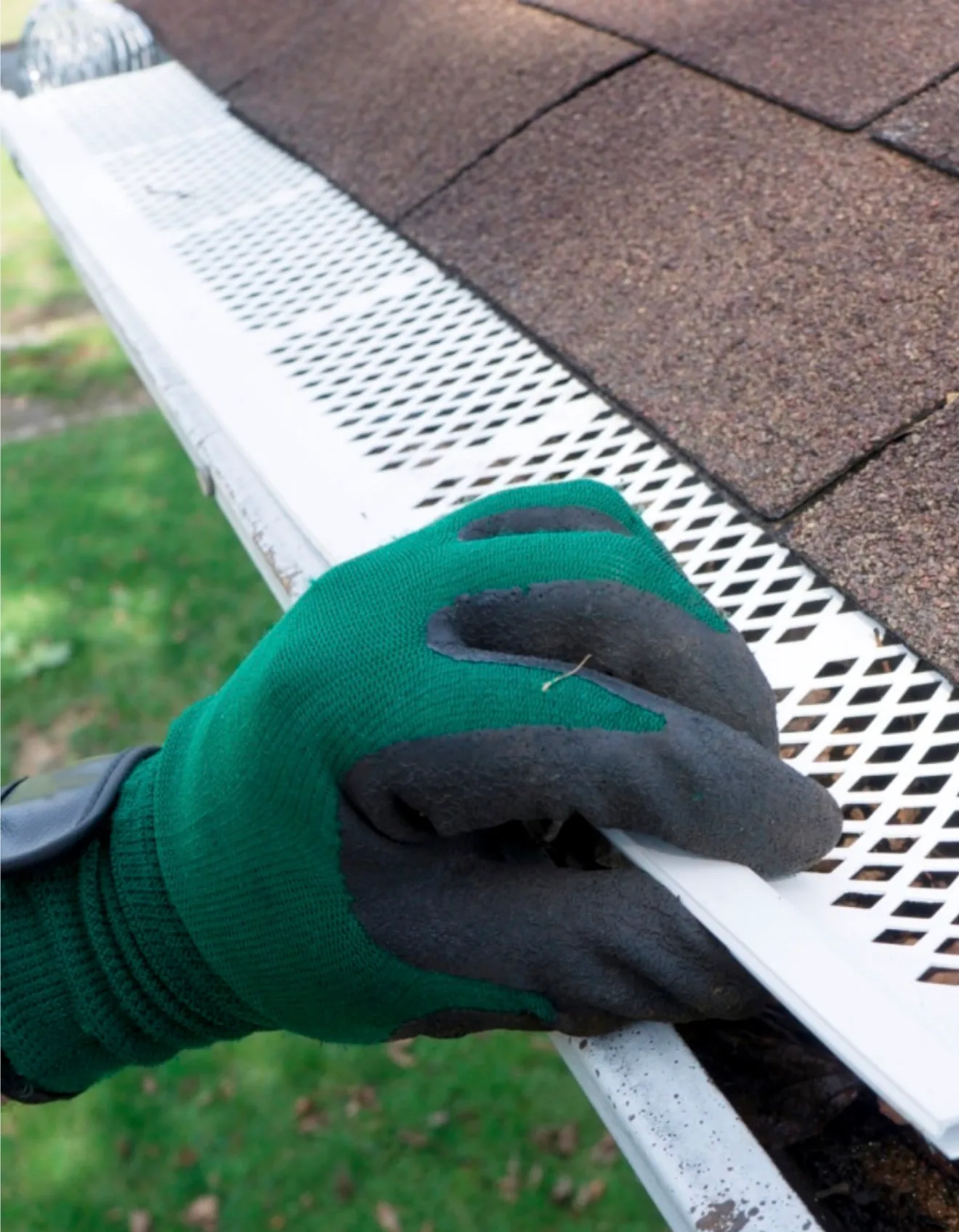 Professional installing protective gutter guards and mesh system on residential shingle roof
