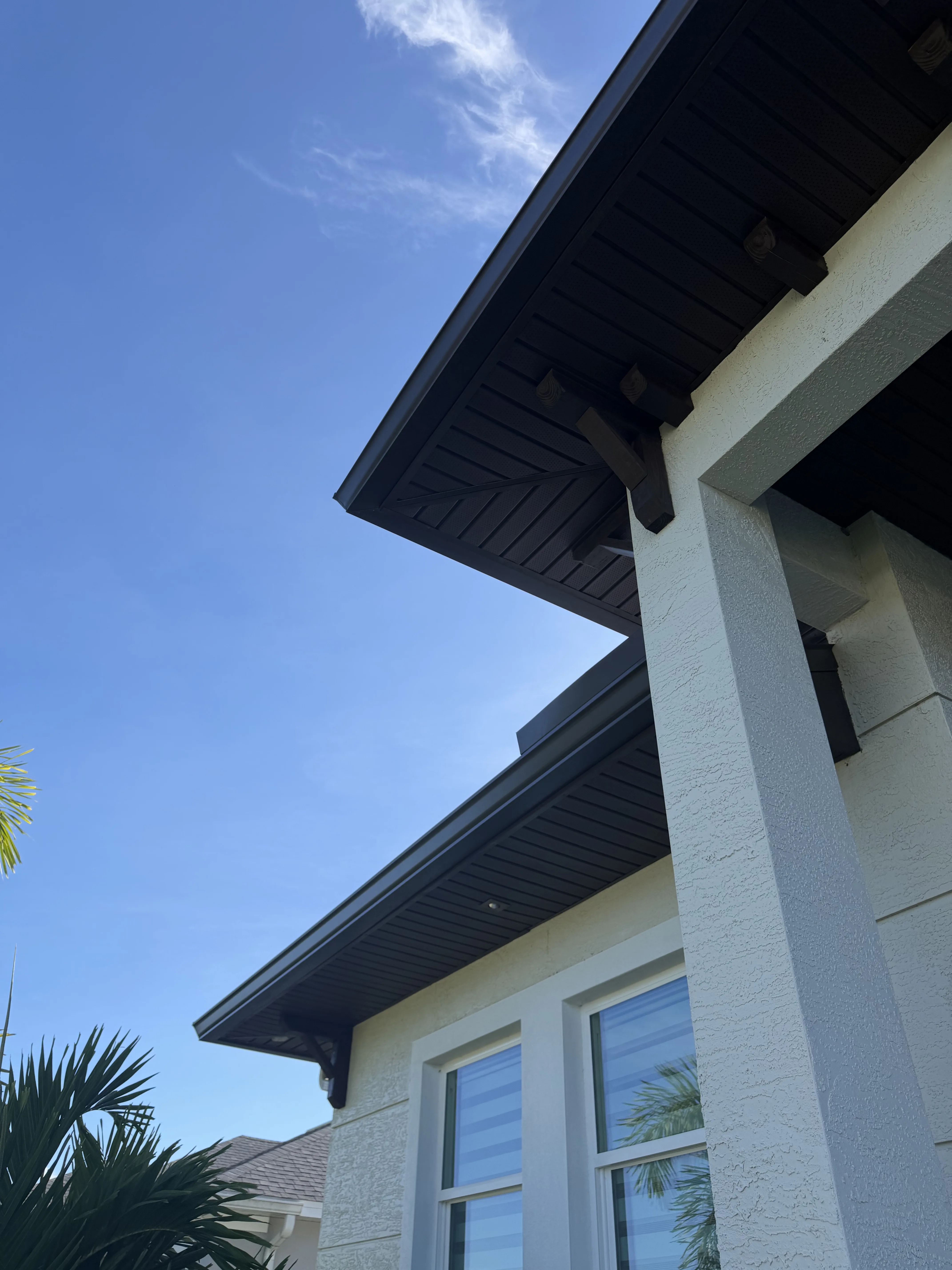 Dark metal gutter and soffit installation on residential home with white exterior