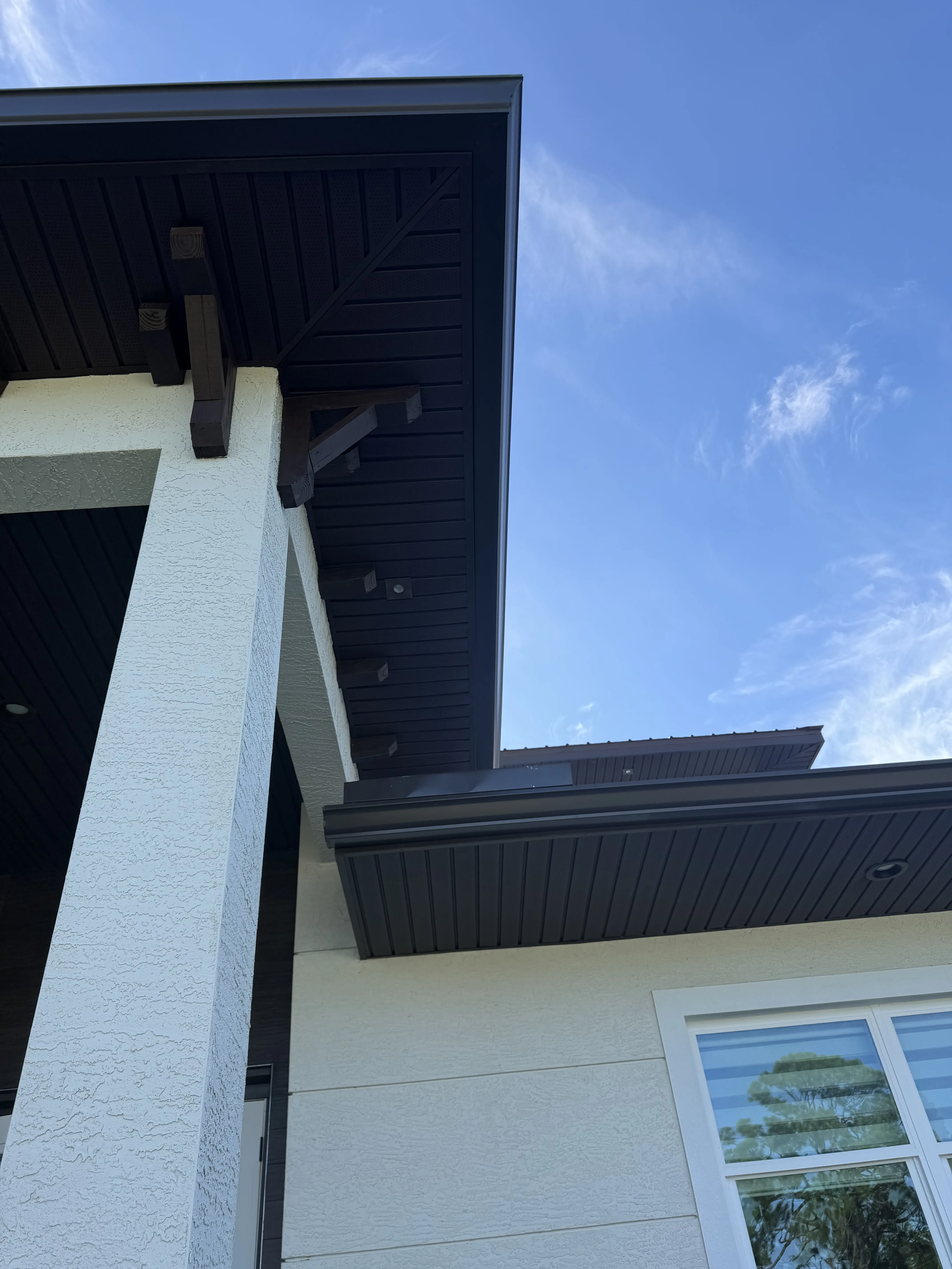 Home exterior with black standing seam metal roof, white brick walls, and modern windows
