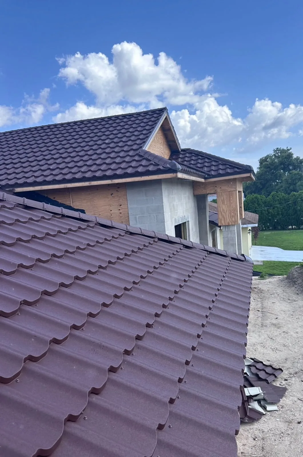 Metal Roof Tiles installation showing burgundy colored metal shingles with wavy pattern on residential roofing project