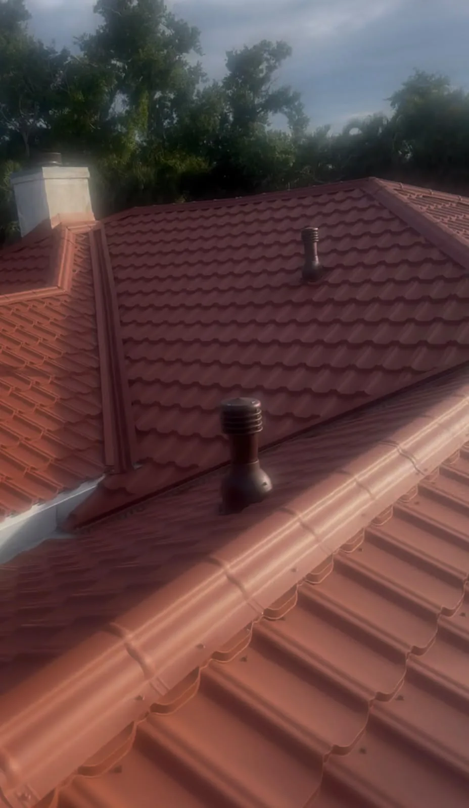 Stone coated steel metal roof with red shingles and ventilation pipes