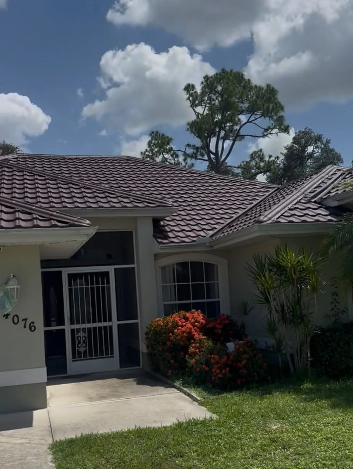 Residential home with professionally installed tile roof featuring dark shingles and manicured front landscaping