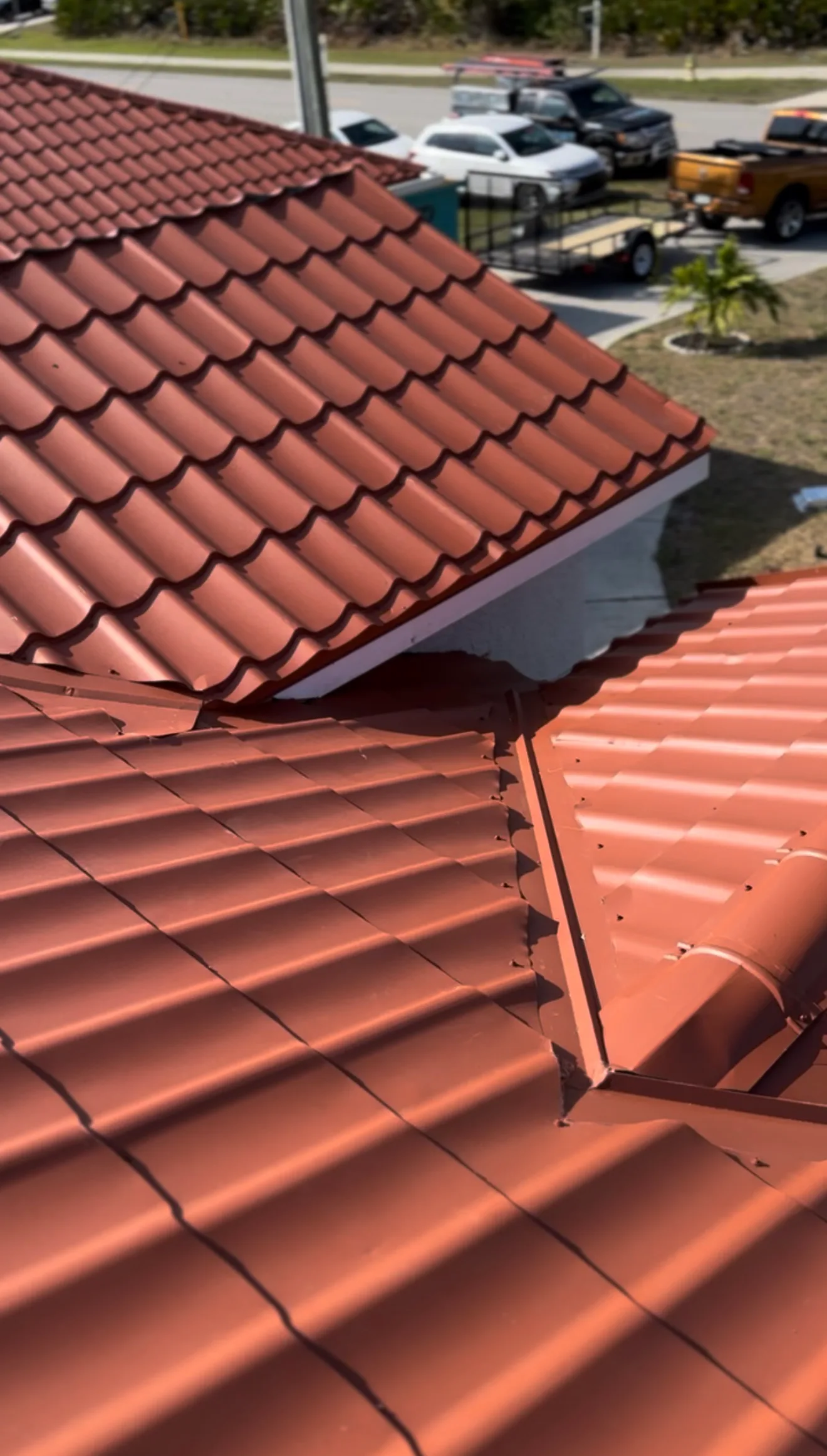 Installed red clay tile roof with visible gutters in residential setting