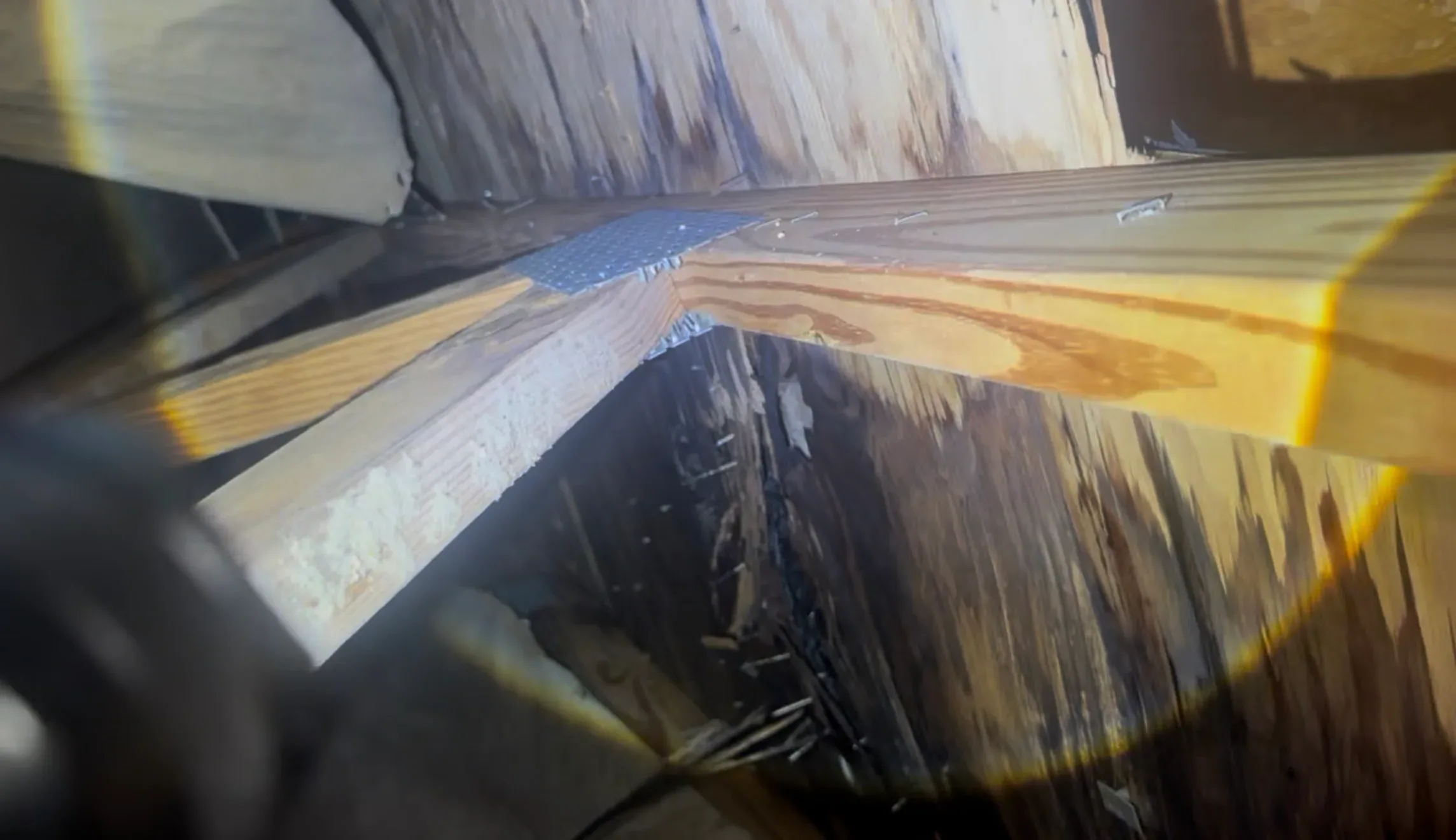 Close-up of damaged roof framing with visible wood deterioration and moisture stains