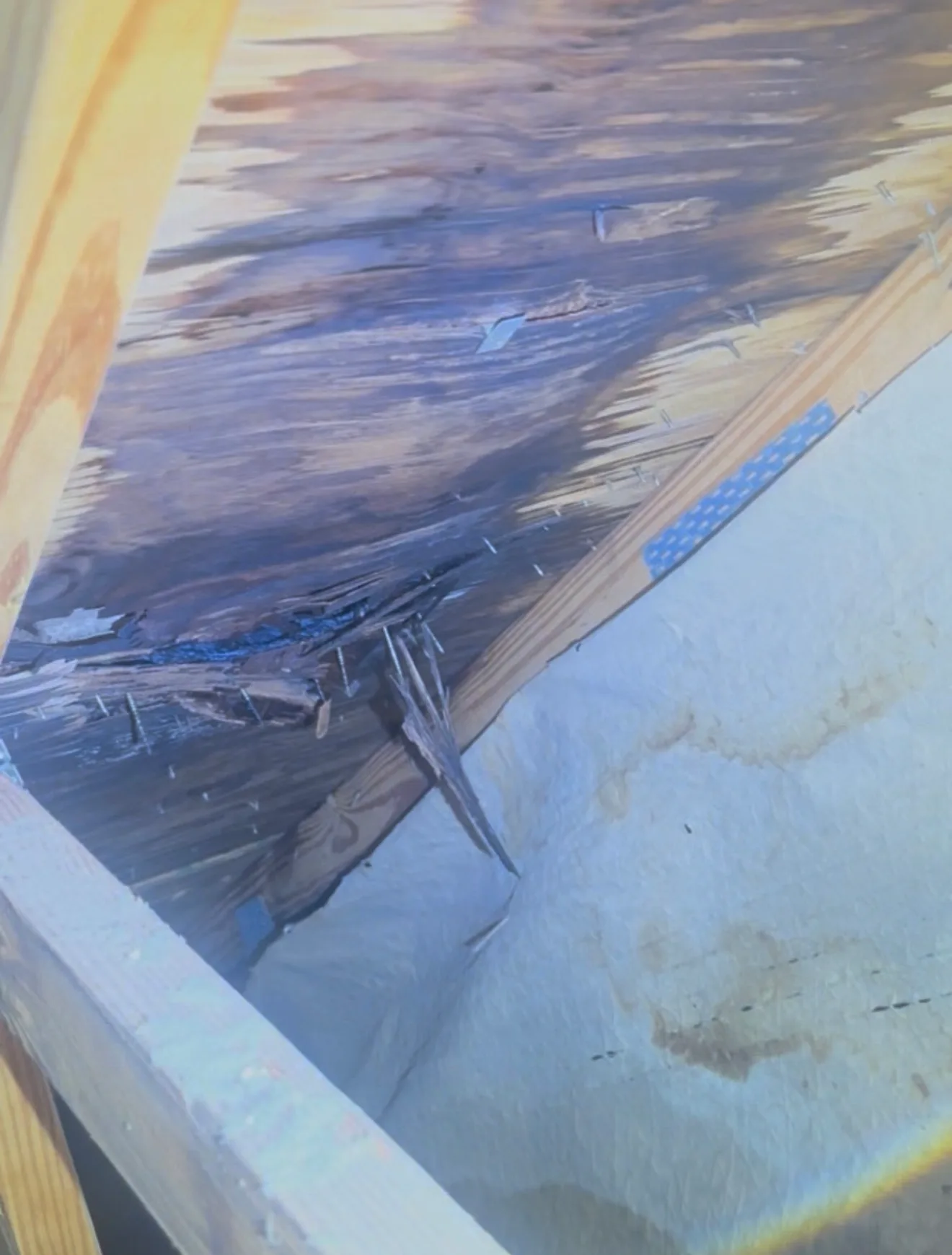 Wooden structural frame covered with protective blue tarp during roof inspection and construction work