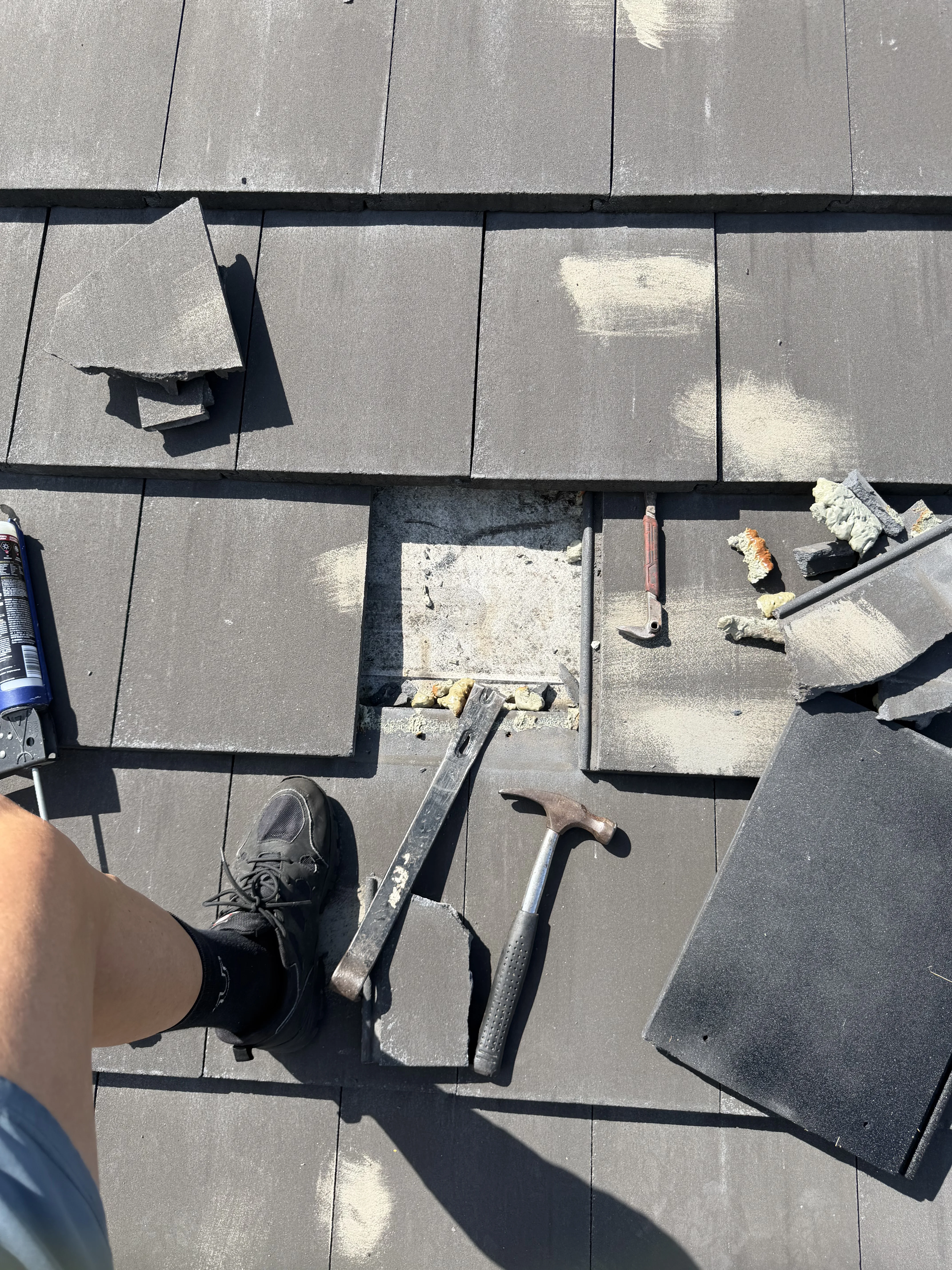 Professional Tile Roof Repair with hand tools on damaged roof shingles