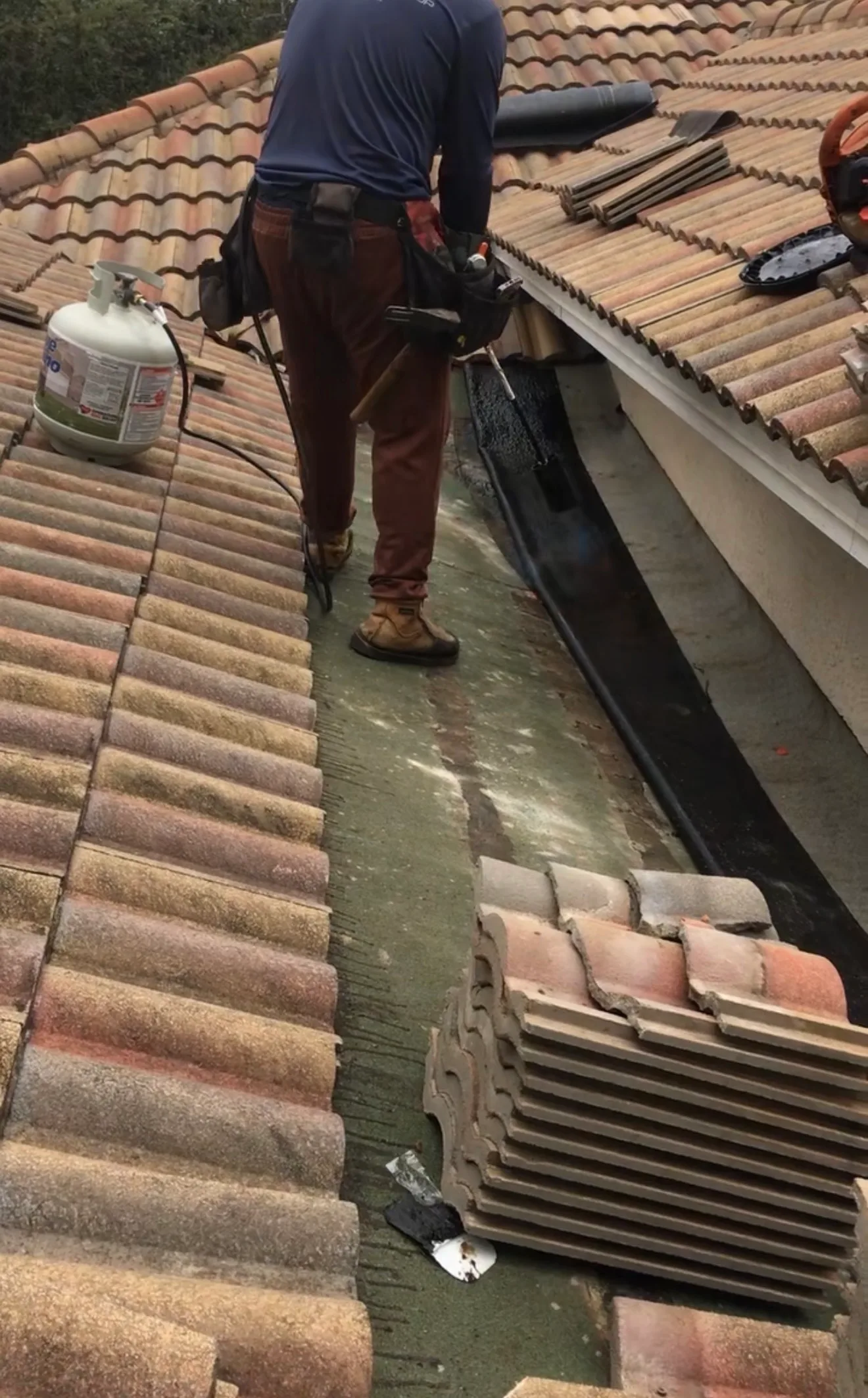 Roofer installing gutter system on tile roof during repair work