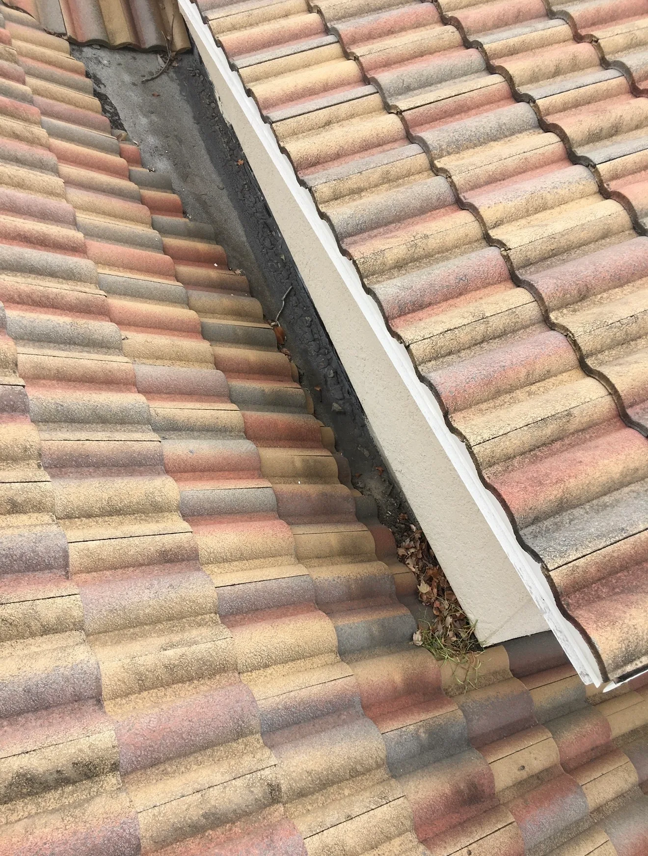 Ceramic tile roof installation showing terracotta shingles with white metal flashing trim