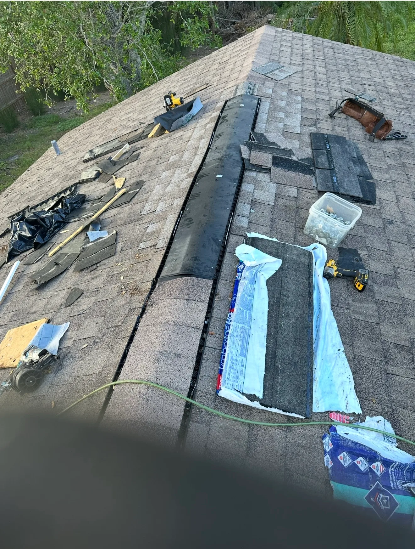 Shingle roof repair in progress showing exposed decking and new roofing materials installation