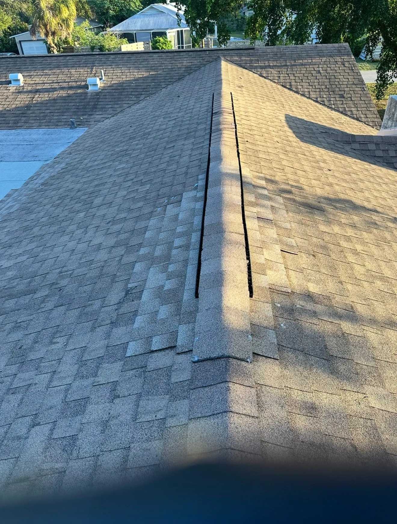 Asphalt shingle roof with ridge caps and seams showing Shingle Roof Replacement work in progress