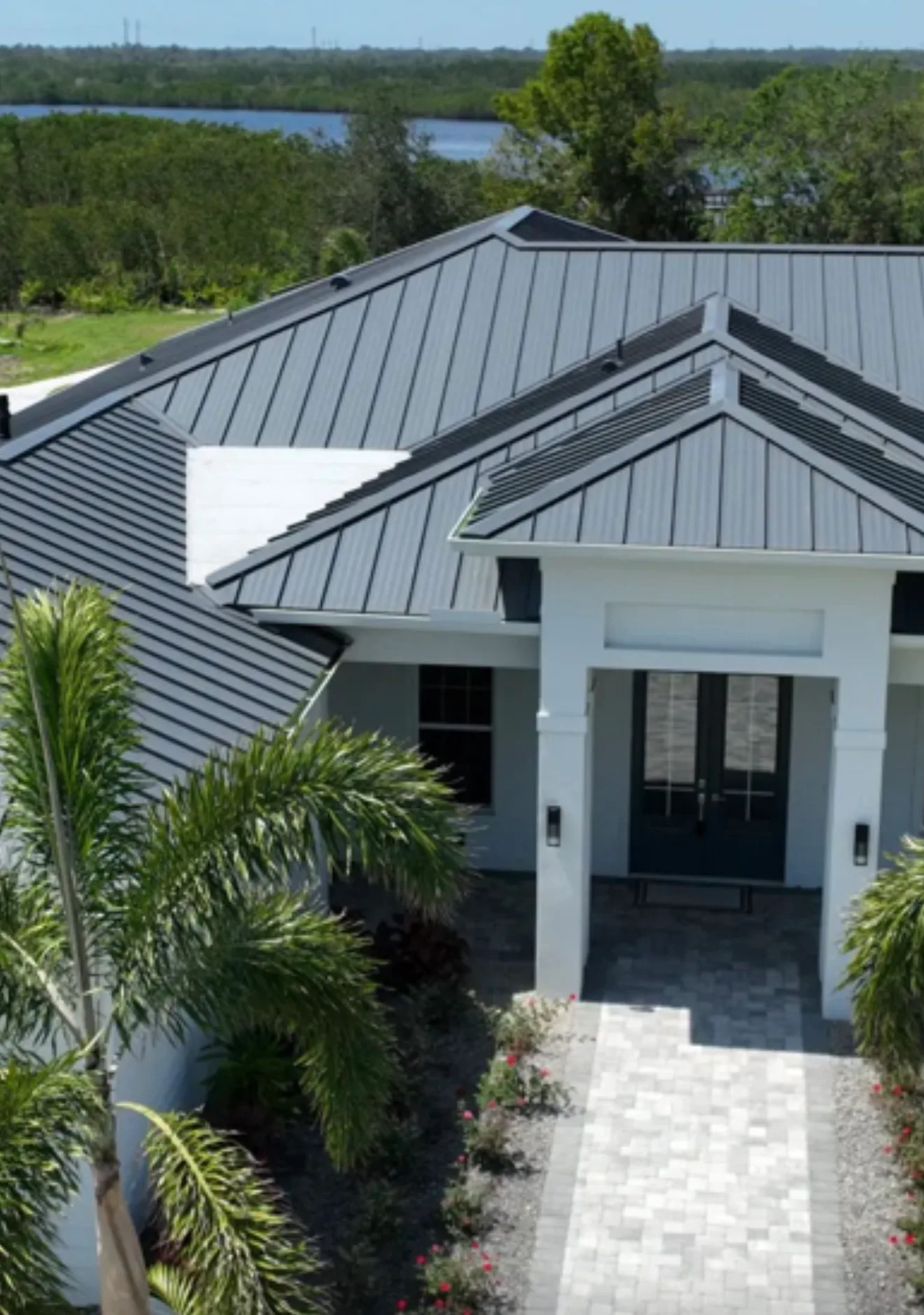 Black standing seam metal roof installed on modern residential home with white entry columns