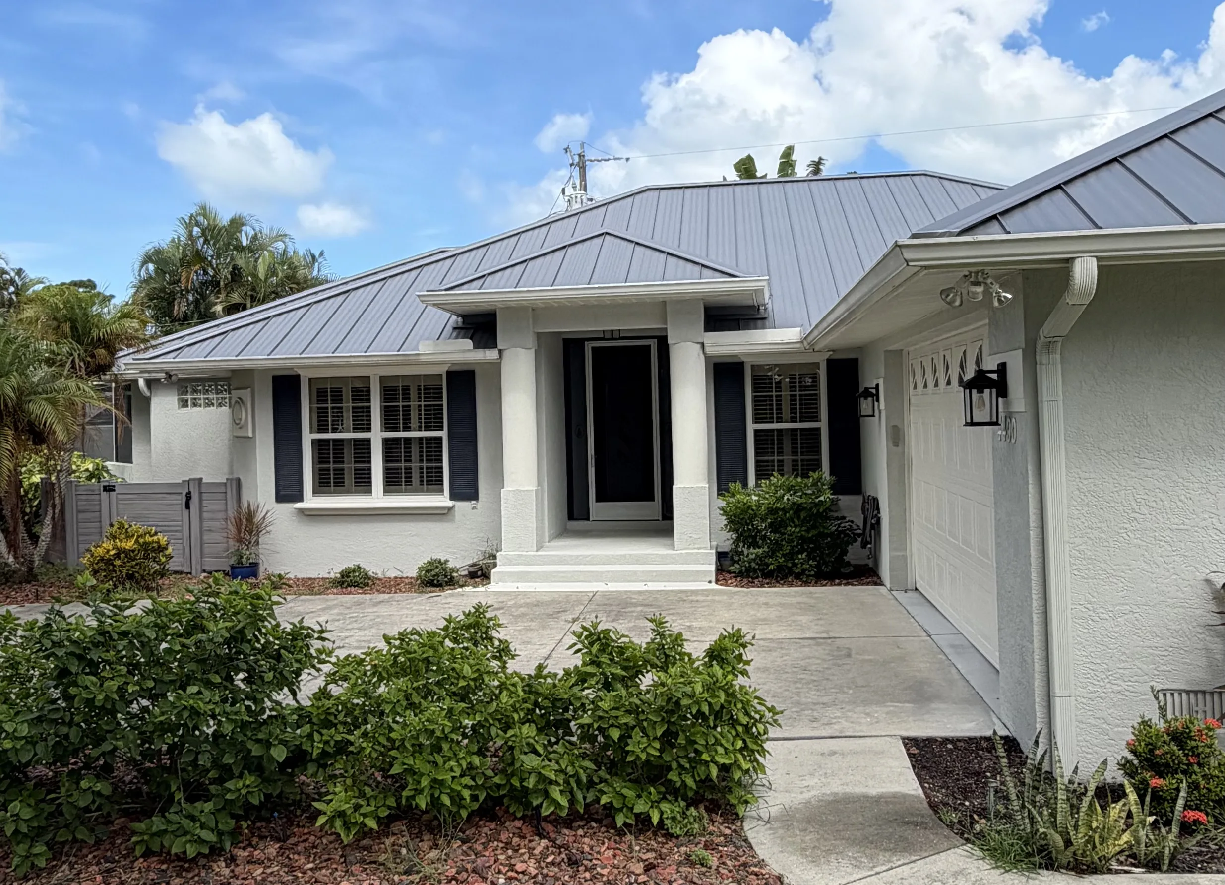Residential home with standing seam metal roof and white exterior with garage