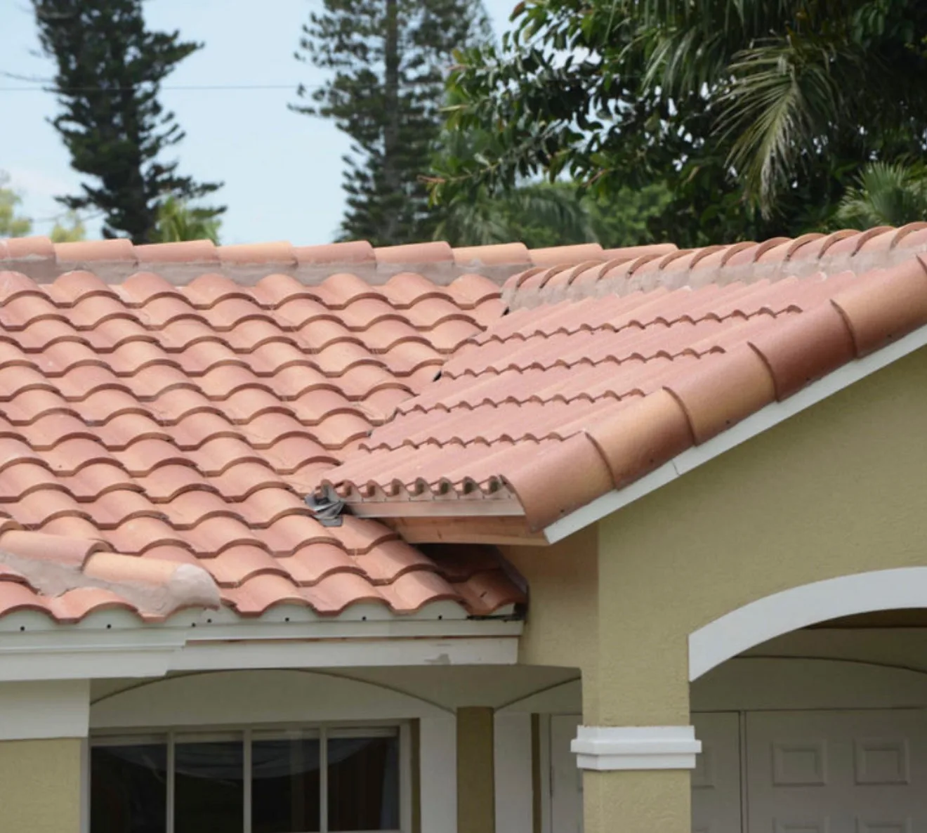 Residential terracotta tile roof with interlocking red tiles, white trim, and roof details