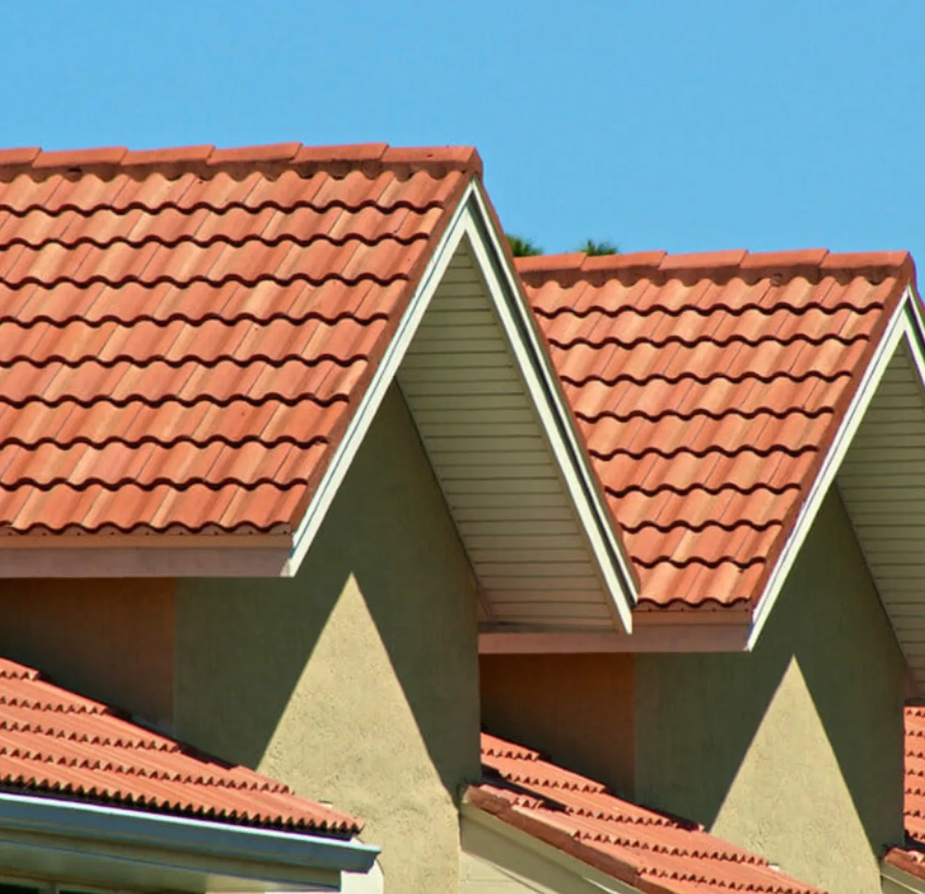 Tile roof replacement featuring pitched terracotta clay tiles with white trim and soffit details